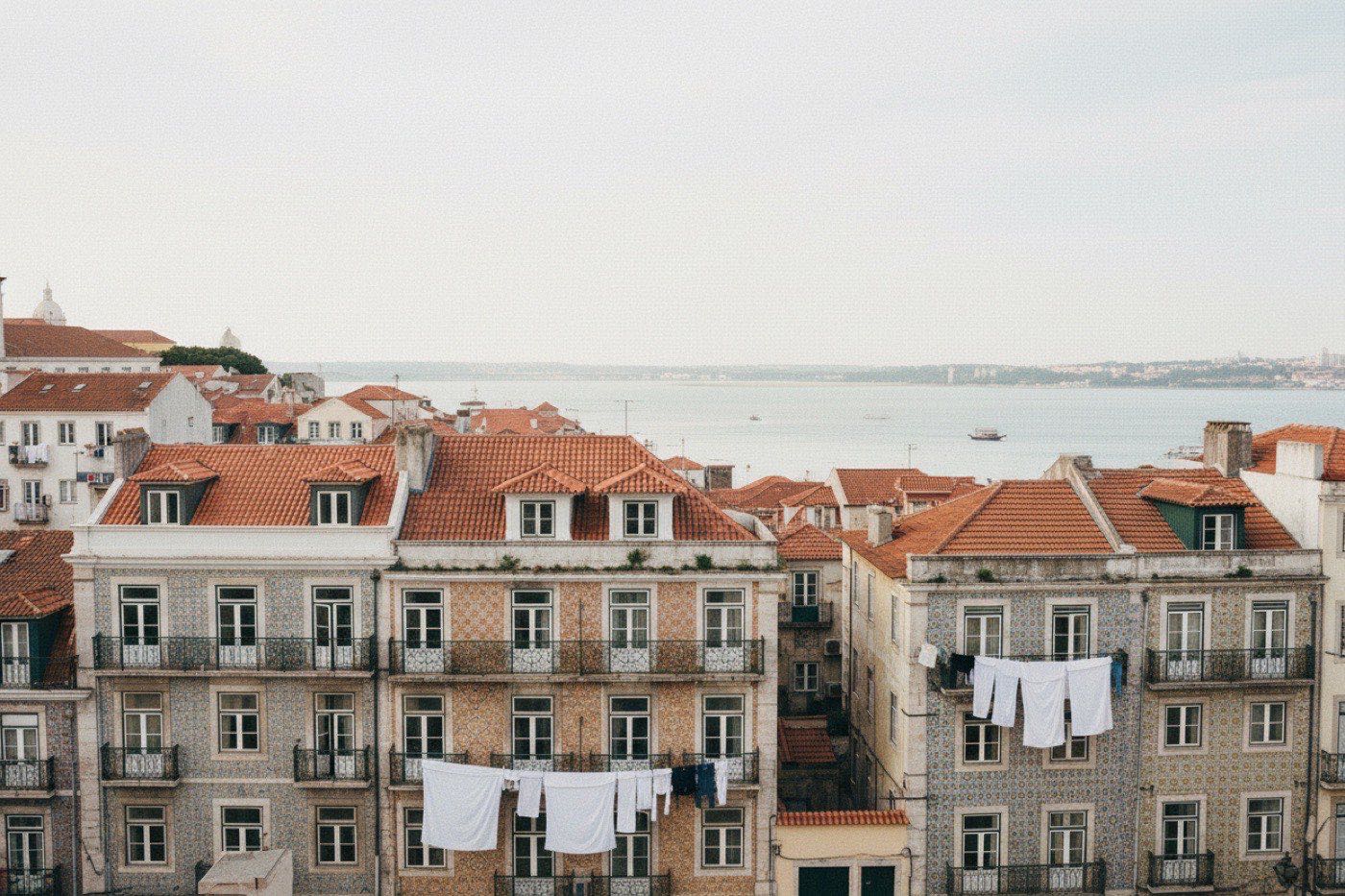 Tiled Lisbon facades above the Tagus, washing strung between the balconies